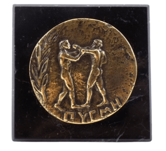 Pisapapeles, moneda de bronce con la efigie de los Pugilistas o Boxeadores, Juegos Olímpicos de Atenas