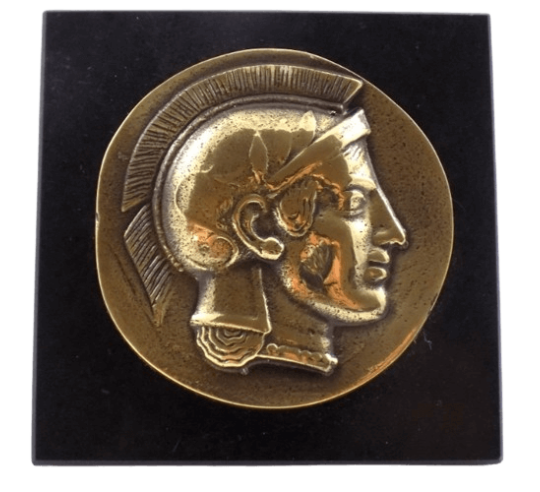 Pisapapeles, moneda de bronce con la efigie del guerrero hoplita griego, símbolo de fuerza y coraje